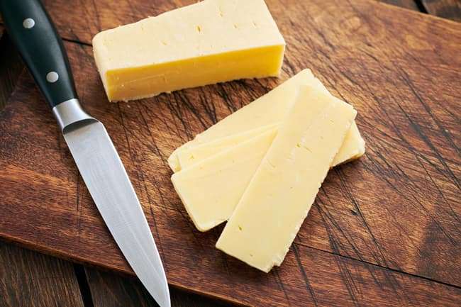 photo of sliced cheddar cheese on cutting board