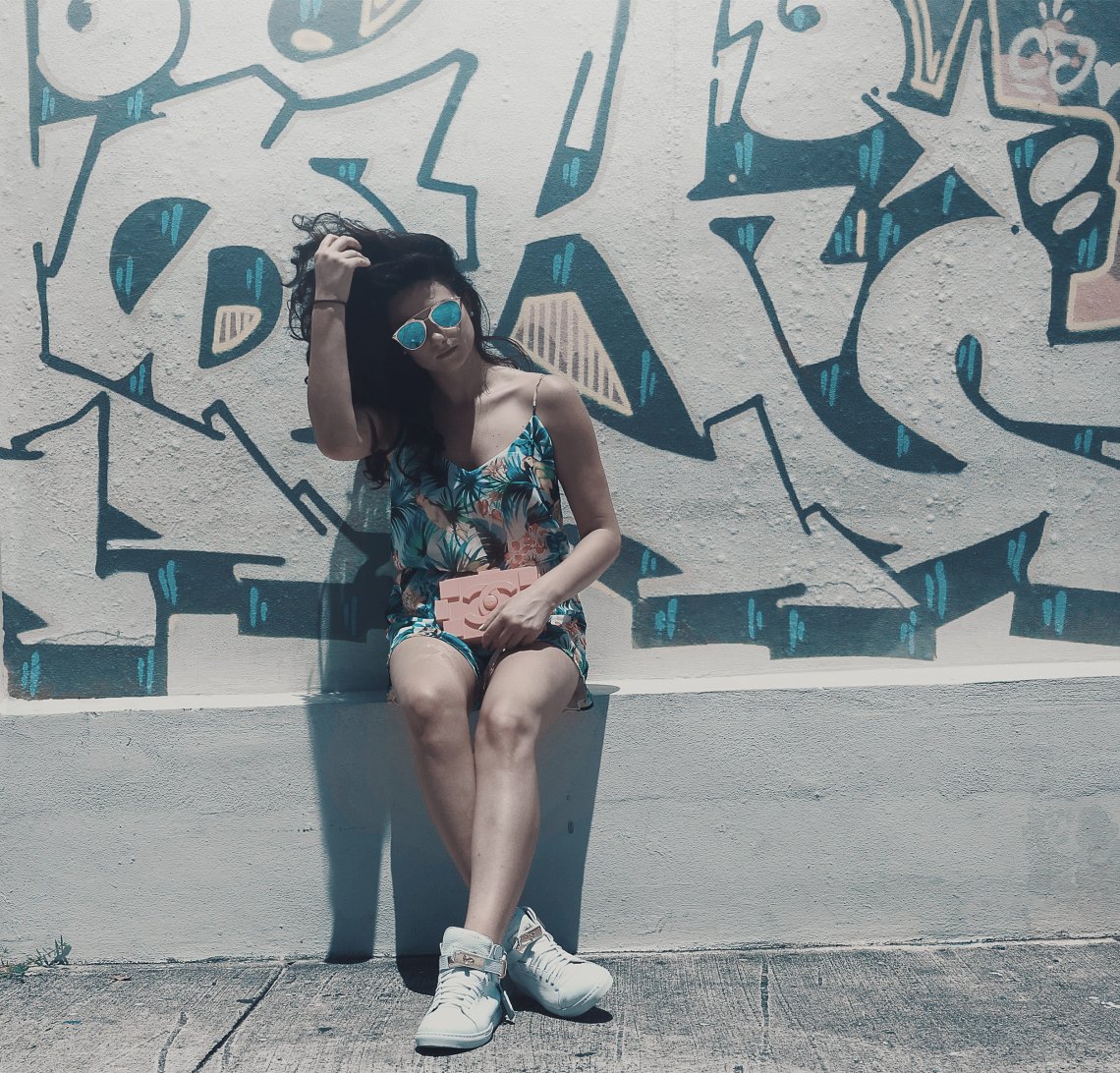 girl sitting in front of grafitti