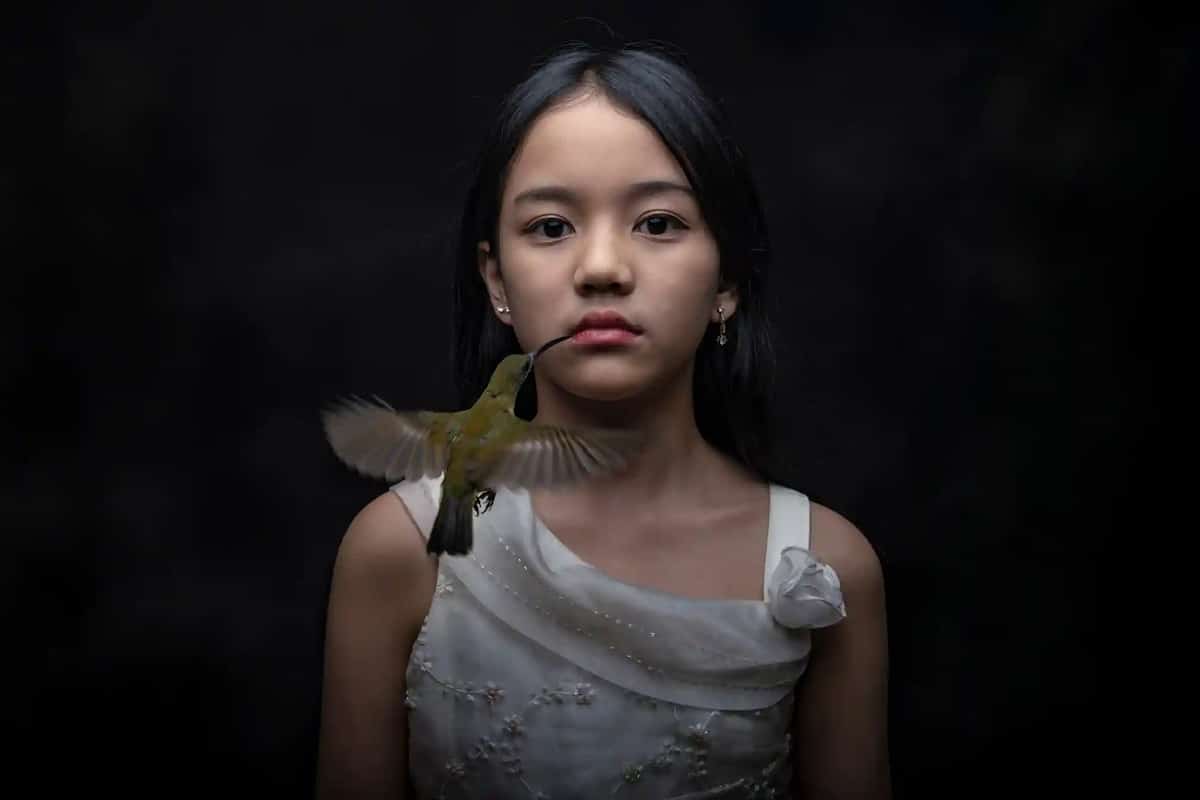 Girl with a hummingbird at her mouth